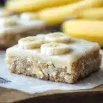 Homemade banana bars topped with nuts and chocolate in a baking dish
