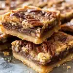 Delicious Brown Butter Pecan Pie Bars topped with pecans and caramel drizzle.
