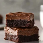 Chewy fudgy frosted brownies with rich chocolate glaze on a white plate