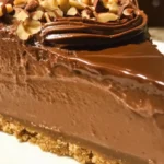Delicious no-bake Nutella cheesecake topped with chocolate drizzle and hazelnuts.