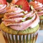 Pistachio cupcakes topped with strawberry buttercream frosting