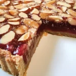 A delicious slice of Raspberry Bakewell Tart topped with fresh raspberries.