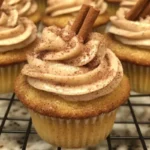 Delicious snickerdoodle cupcakes with cinnamon swirl frosting on a plate.