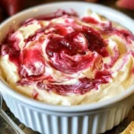 Bowl of creamy strawberry cheesecake dip with fresh strawberries on top