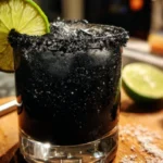 A refreshing Black Margarita garnished with lime and served in a salt-rimmed glass.