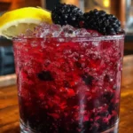 A refreshing Classic Bramble cocktail garnished with blackberries and lemon.