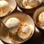 Delicious homemade coconut ice cream in a bowl topped with shredded coconut.
