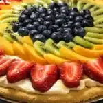 Colorful fruit pizza topped with fresh fruits and creamy frosting on a crust.