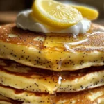 Plate of Greek yogurt lemon poppy seed pancakes topped with fresh fruit.