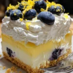 Slice of Lemon Blueberry Cheesecake topped with fresh blueberries and lemon zest