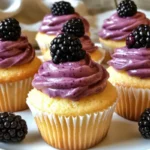 Lemon cupcakes with blackberry cream cheese frosting on a white plate