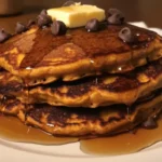 Fluffy pumpkin pancakes drizzled with syrup on a plate