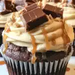 Ultimate Snickers Cupcakes topped with caramel and peanuts